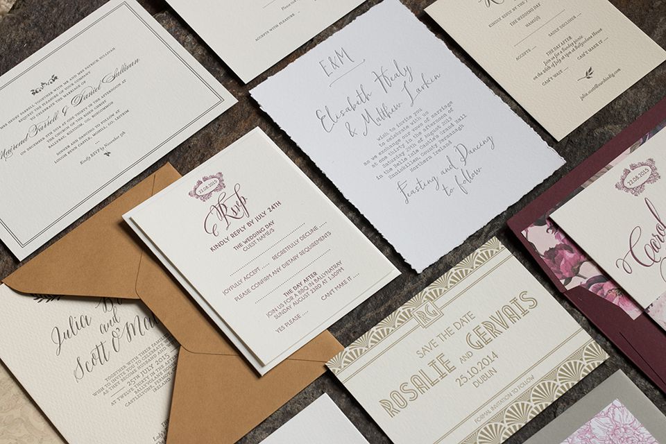 Collection of letterpress wedding invitations in various inks resting on a flat surface