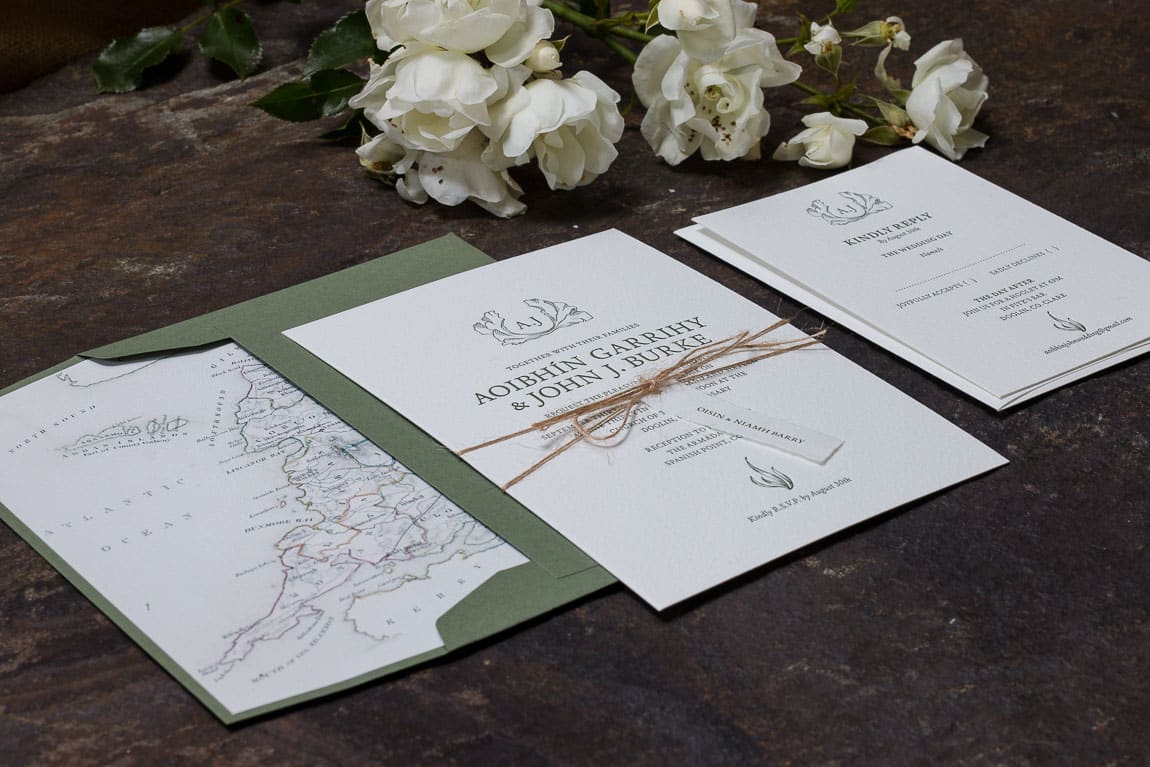 Wedding Invitation with name tag tied around it resting on green envelope with an envelope liner showing County Clare in Ireland